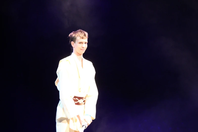 a man wearing a white outfit on stage