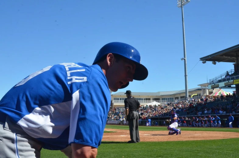 a baseball player leans back at the base as other players look on