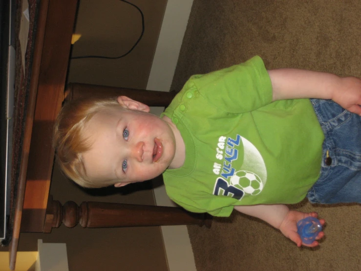 a small toddler is holding soing under the table