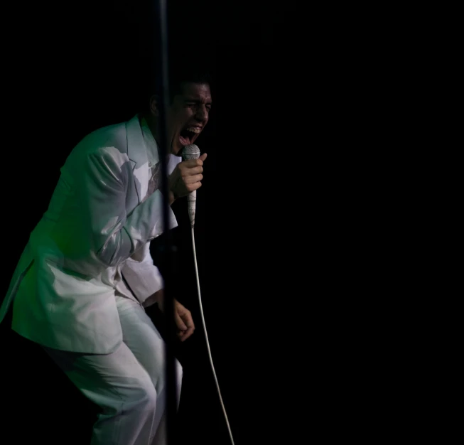 a singer with a white suit and white pants and microphone