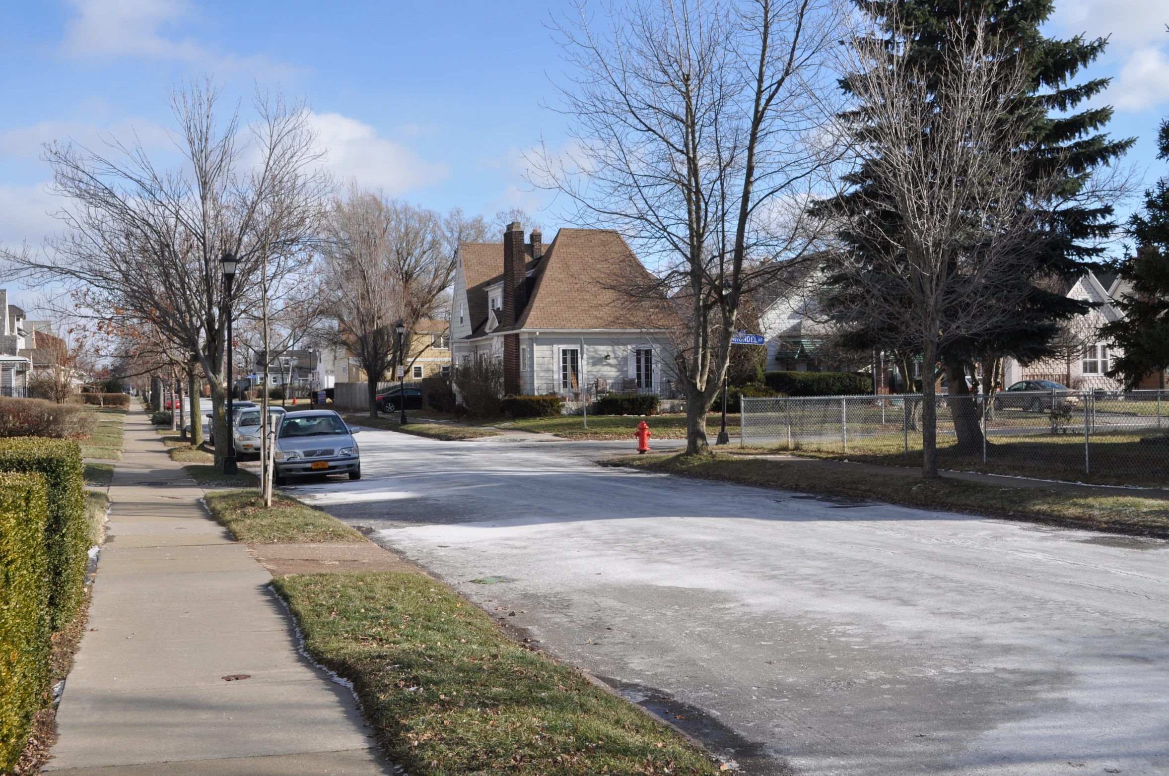 an empty street with parked cars and houses