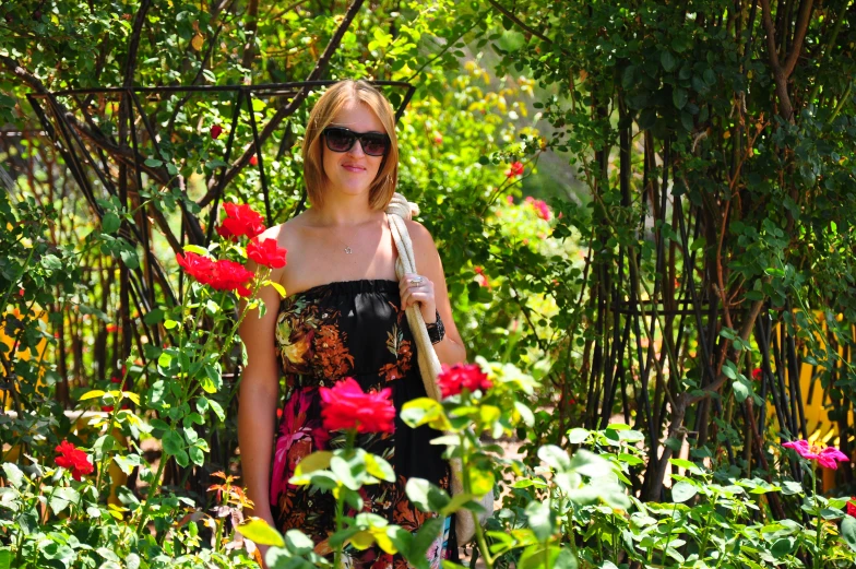 a woman in a floraled dress with a pink flower and green foliage