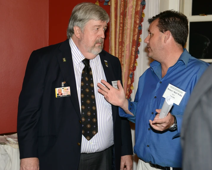 a man talking to another man in a suit and tie