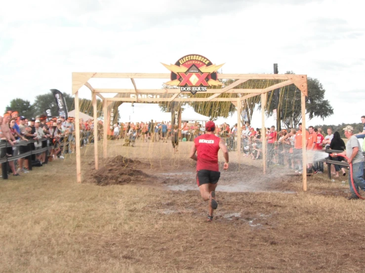 a man running down a dirt road as people watch him