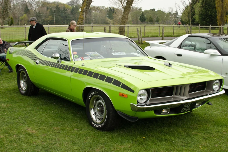 a bright green muscle car parked on top of a grass field