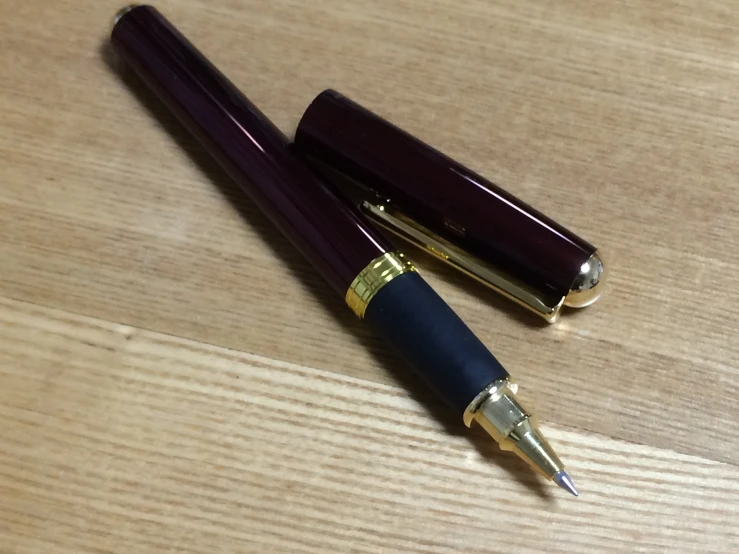 two fountain pens sitting on top of a wooden table