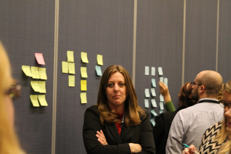 a group of people standing around a wall with post - it notes