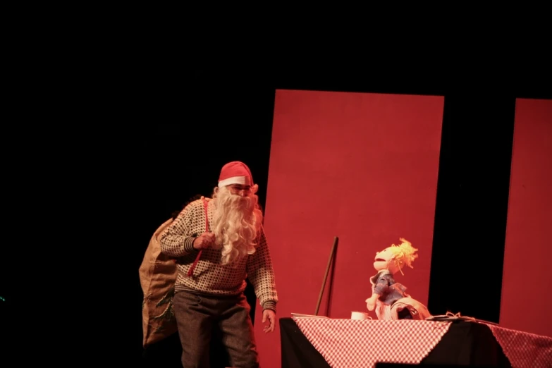 a man with a santa hat walking on stage next to an animated character