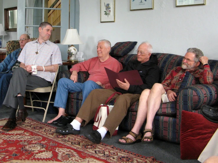 a group of people sitting on a couch with one holding a folder and another standing