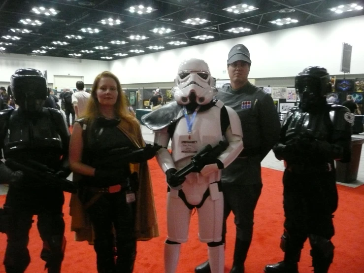 a woman with glasses, standing next to men in costume