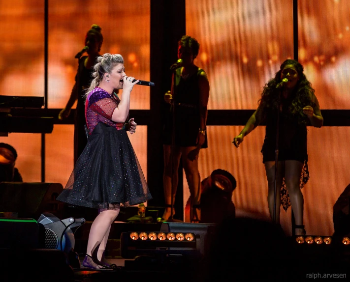 a female singer on stage with music in the background