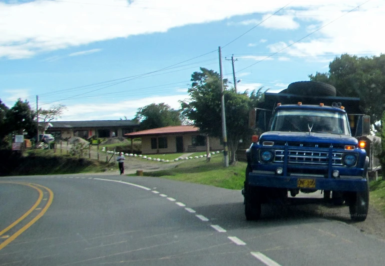 a blue truck with luggage on the back is traveling down the road