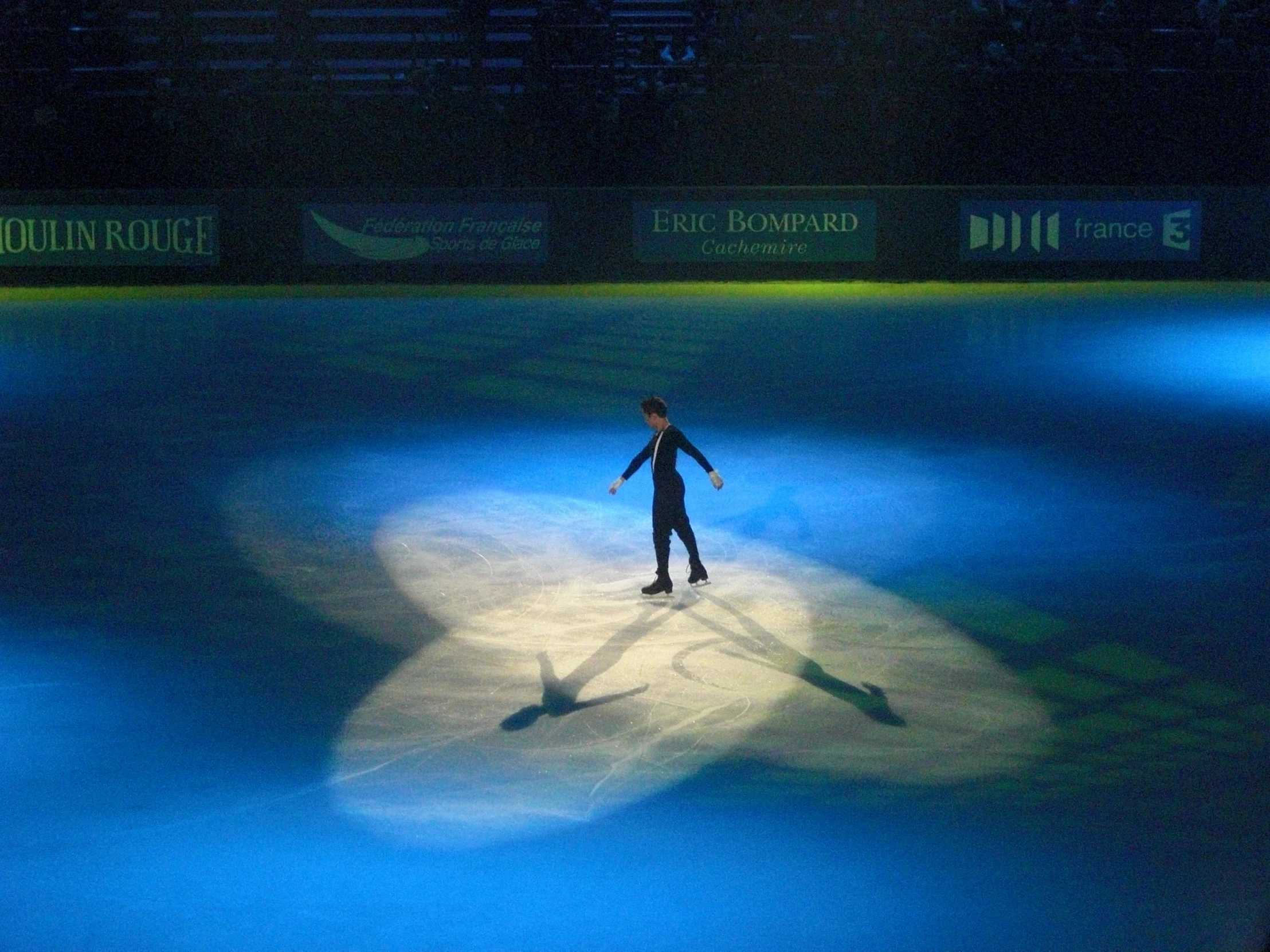 a man standing on top of an ice rink in the dark