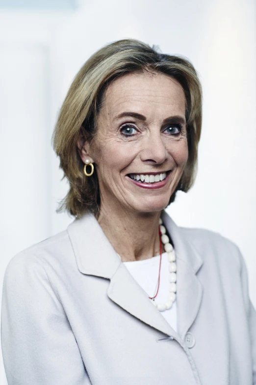 a close up of a person wearing a pearl necklace and jacket