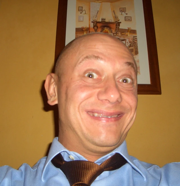 smiling man with shaved head wearing a tie