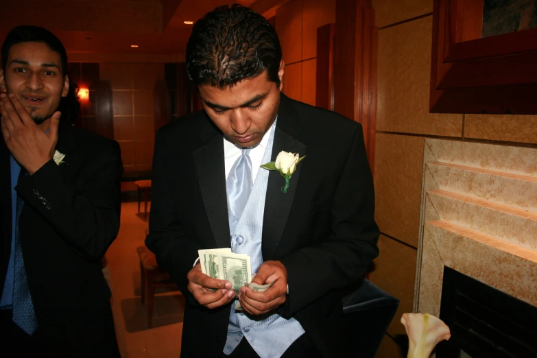 a man in a black suit holds a bundle of money