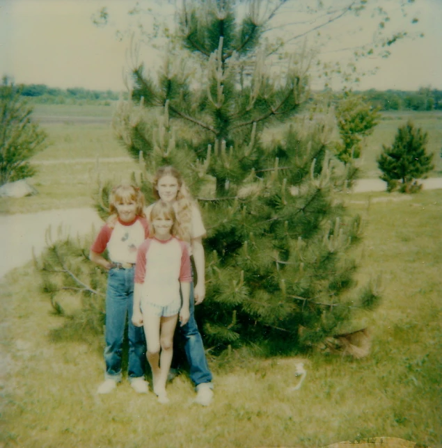 a black and white picture of three children next to a tree