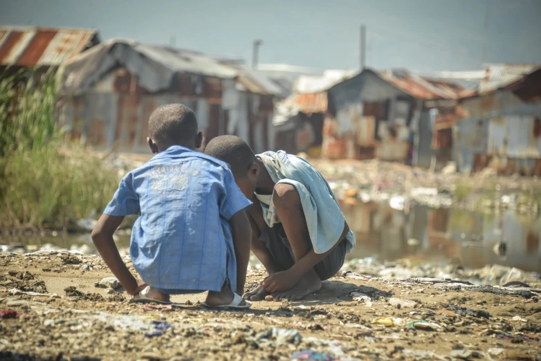 two children playing in the sand with a body of water behind them