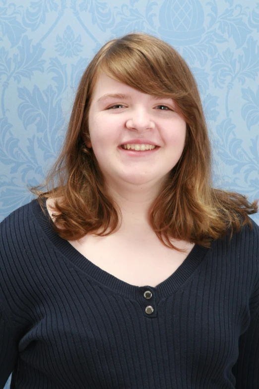 a young lady smiling in front of a blue background