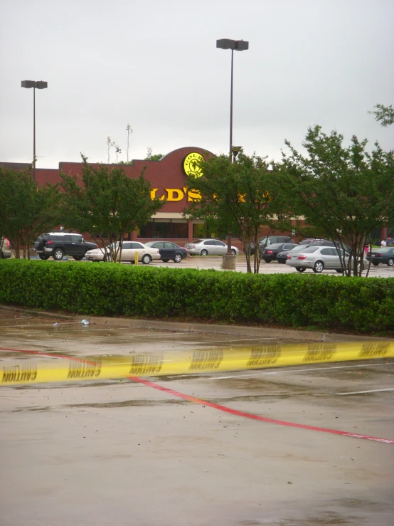 a parking lot with trees, cars, and a yellow tape