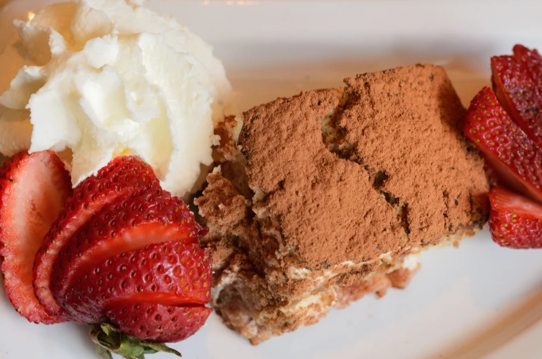 some strawberries on a plate next to a piece of cake and ice cream