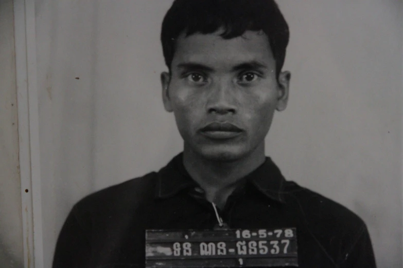 a man with an identification card in a prison uniform