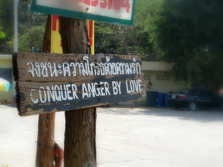 a sign with writing on a wood pole in a parking lot