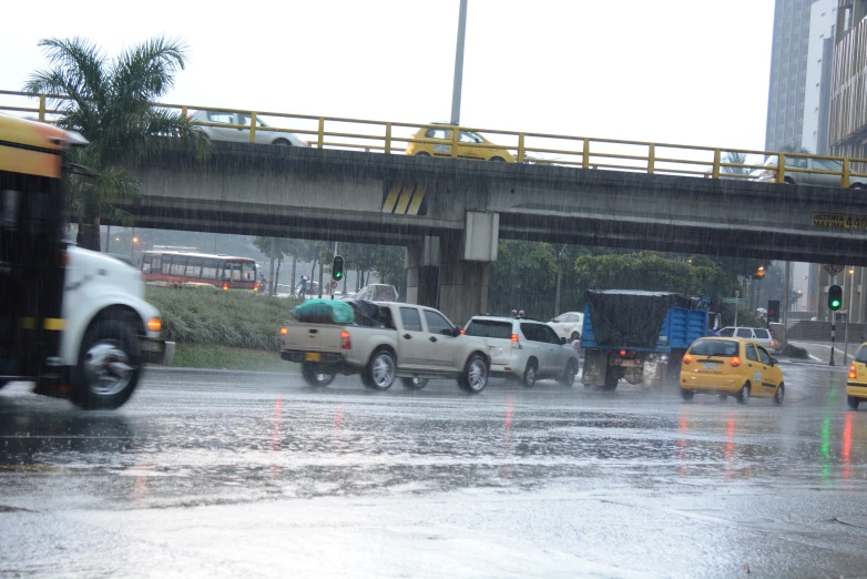 several vehicles and trucks are driving in the rain