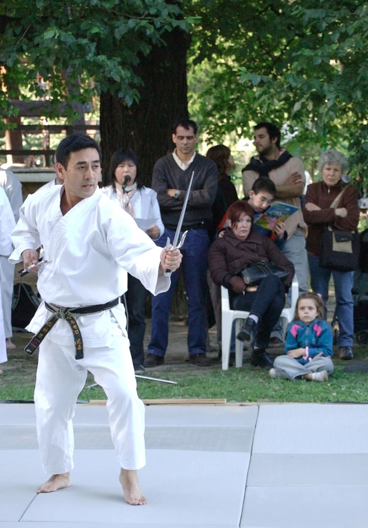 the man is practicing karate moves while others watch