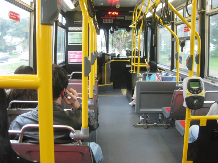 people are seated on the bus talking on their cell phones