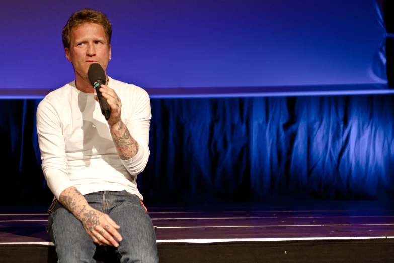 a person sits on the ground while speaking into a microphone