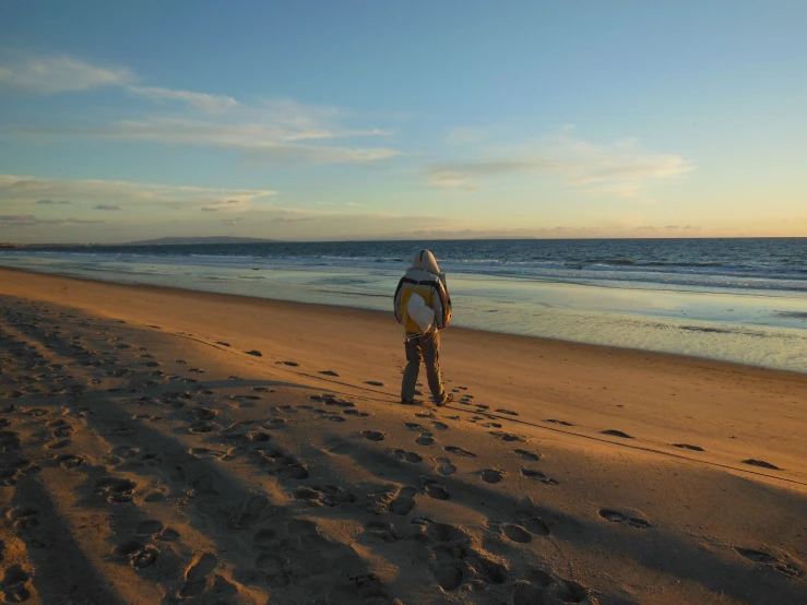 there is a man that is walking down the beach