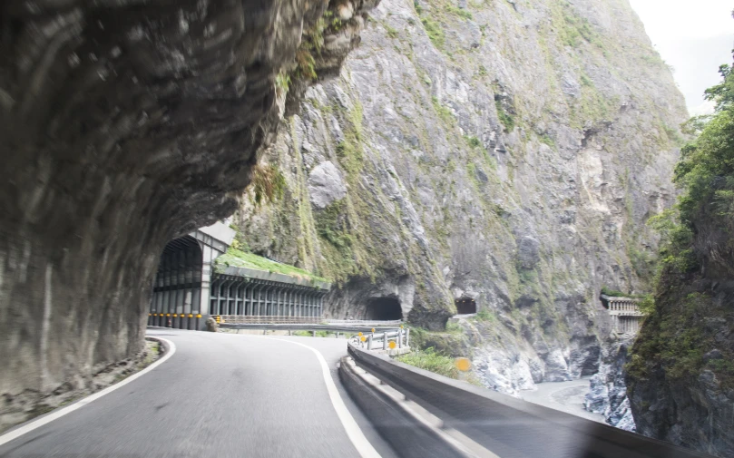 a scenic mountain tunnel with a winding road and the entrance to it