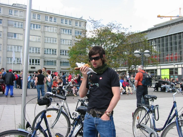 a man standing with food and several parked bicycles