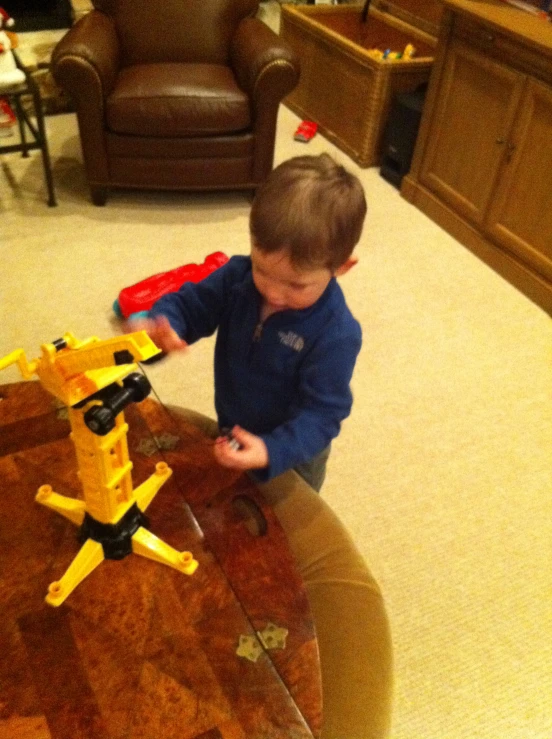 a little boy playing with a yellow and black plane toy