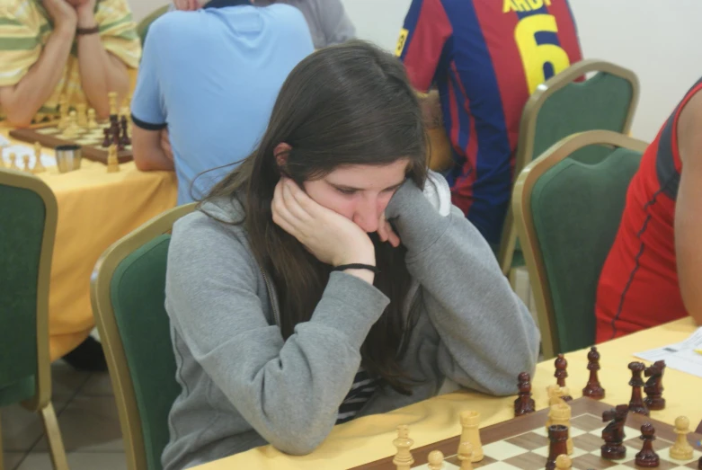 a young woman playing chess in a group