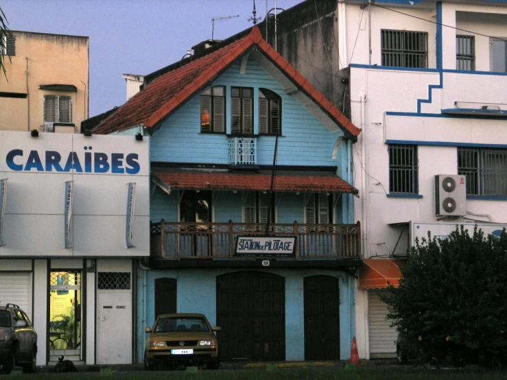 a blue building sitting in front of a tree filled parking lot