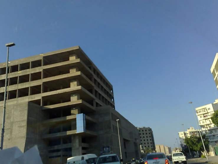 cars sit parked on the street in front of a large building