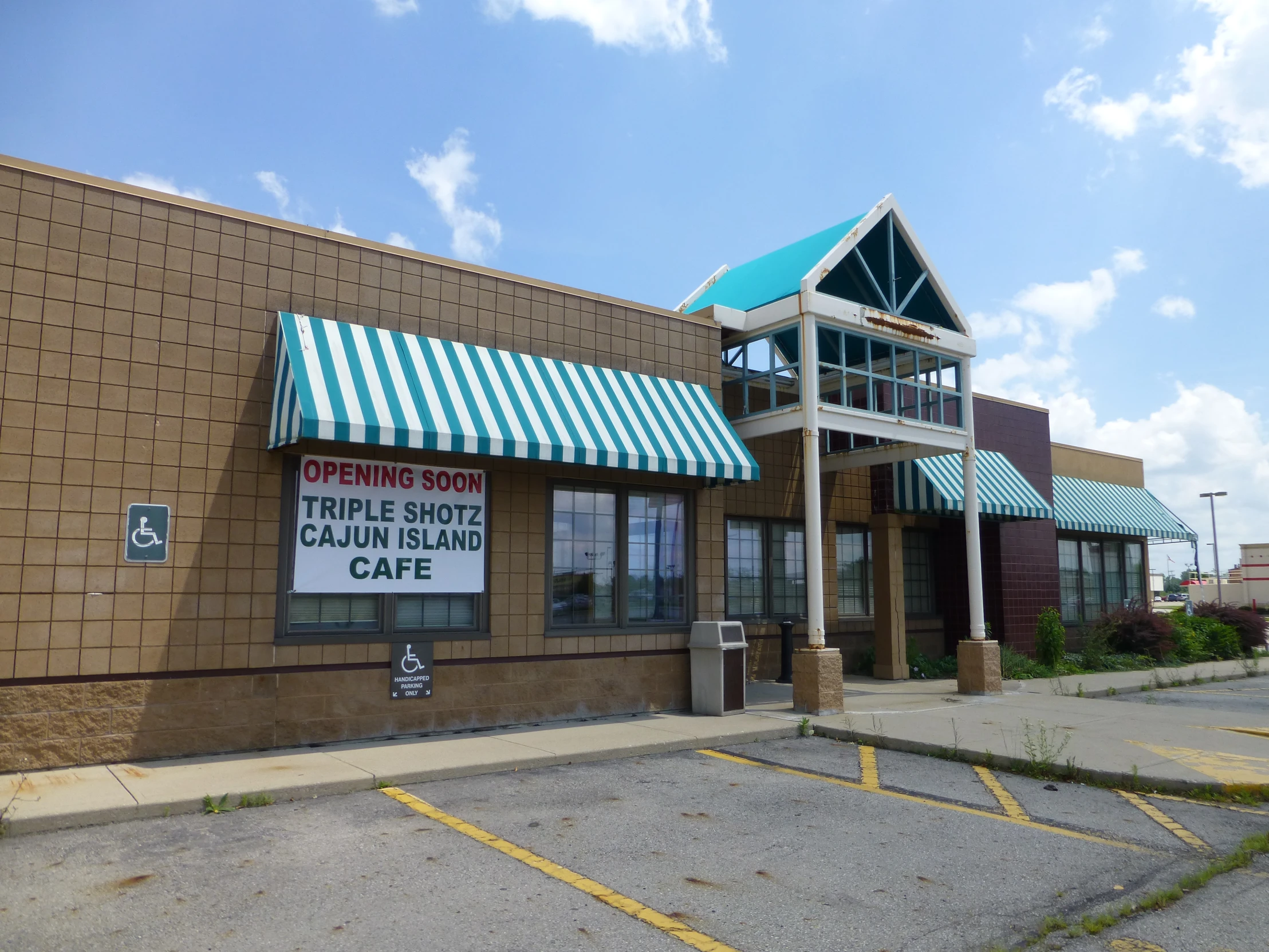 a brown brick building has a awning and blue and white striped sign in front