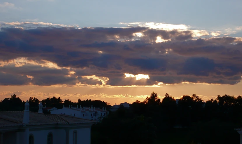 the sunset and clouds are setting over some buildings