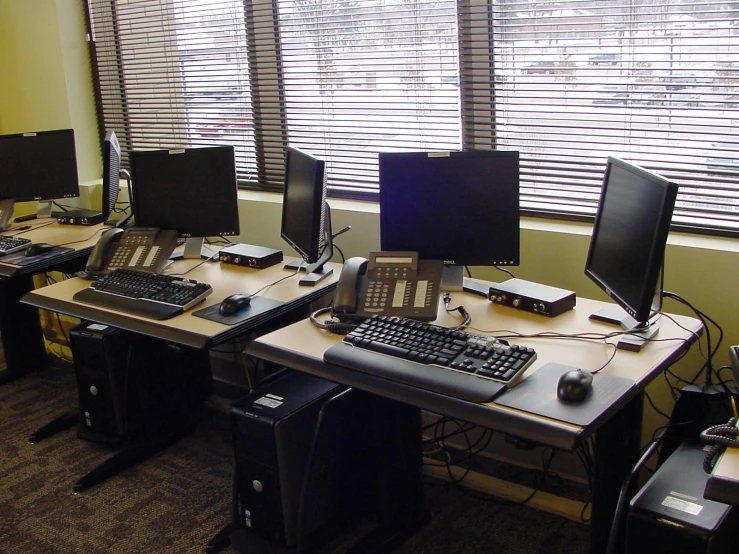 a number of computers on a desk near one another