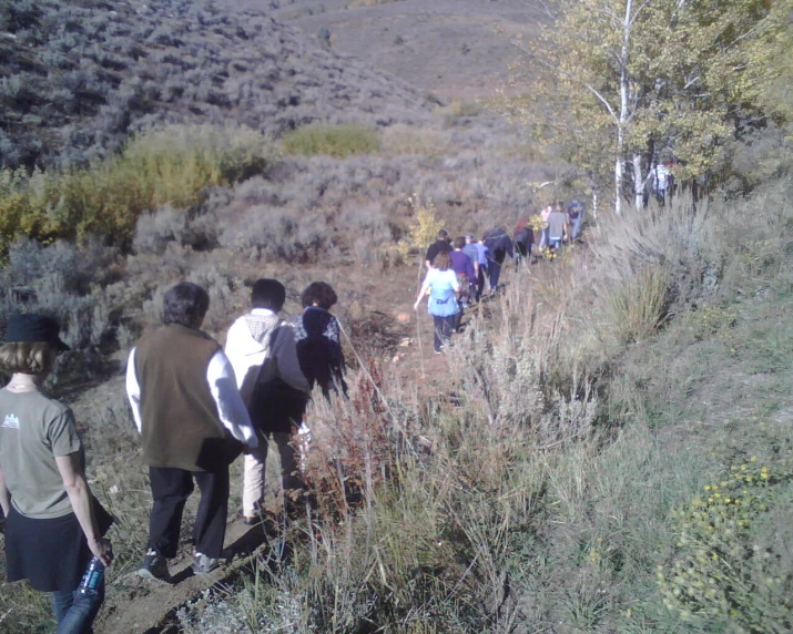 people walking down a hill towards a hillside