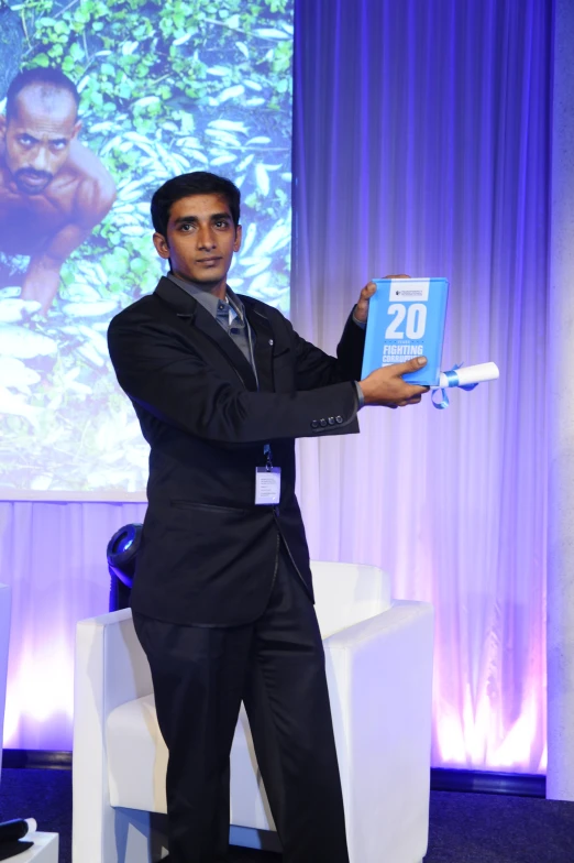 a man in a suit and tie stands with a video game controller