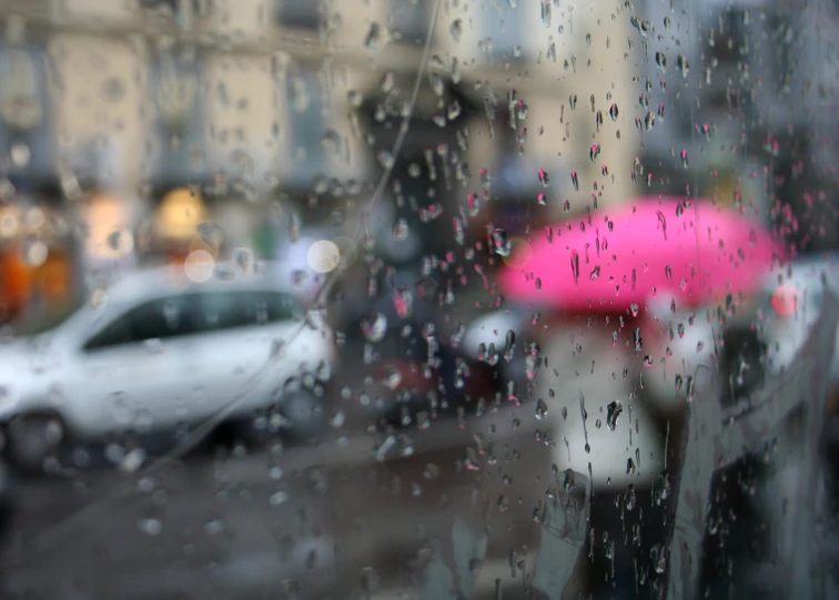 the view of street from inside a building through a window covered in rain