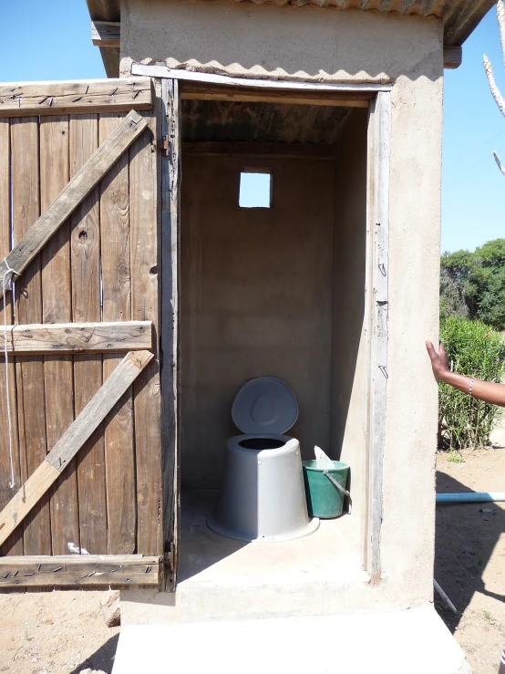 a doorway leading to an outhouse with a plastic pan in it