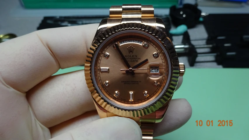 a gold rolex watch sitting in someones hand