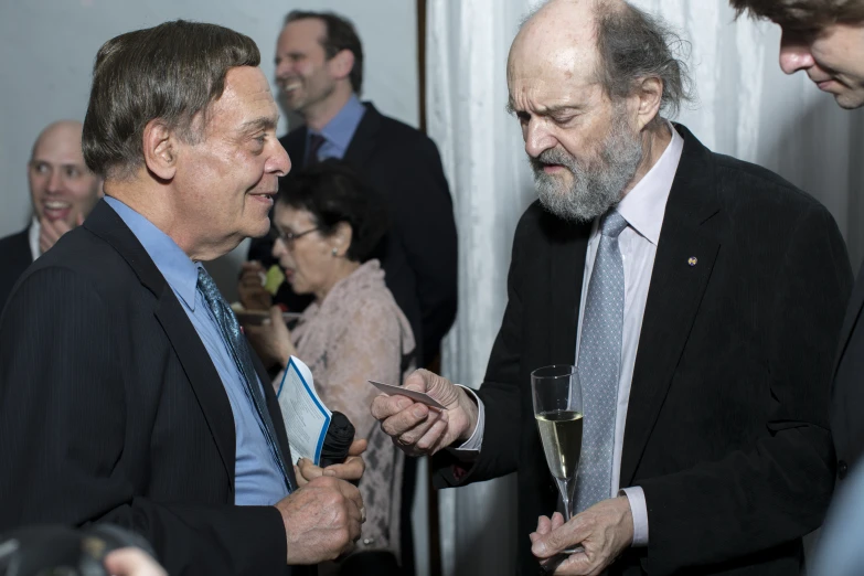 several people in suits and ties smile as they hold champagne glasses