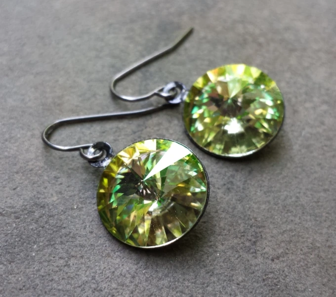 two pairs of green crystal earrings on a gray surface