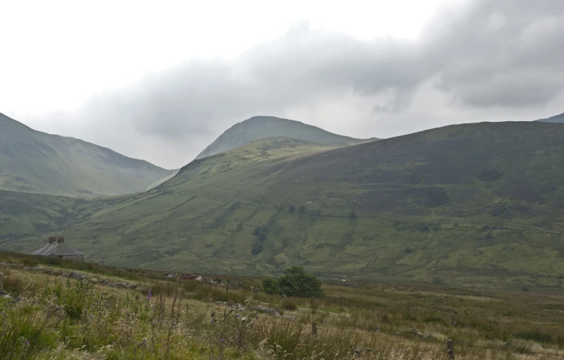 two mountains in the distance with grass in the foreground