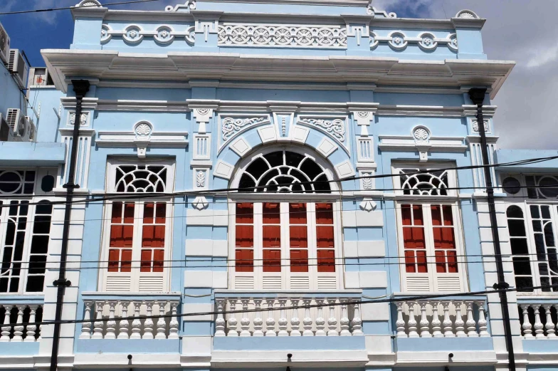 a blue building with red shutters and white trim on the windows